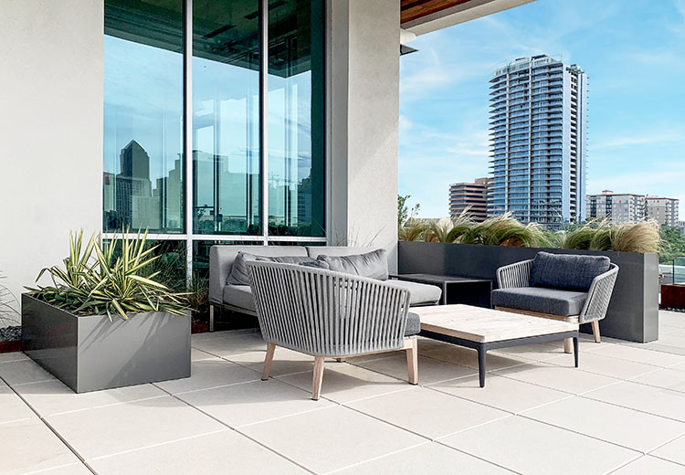 Aluminum Form and Fiber planter box next to outdoor seating area on a rooftop. High rise buildings are in the distance.