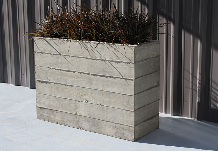Tall, rectangular Form and Fiber concrete outdoor planter. Outlines of the boards used to form the concrete are visible on the outside.