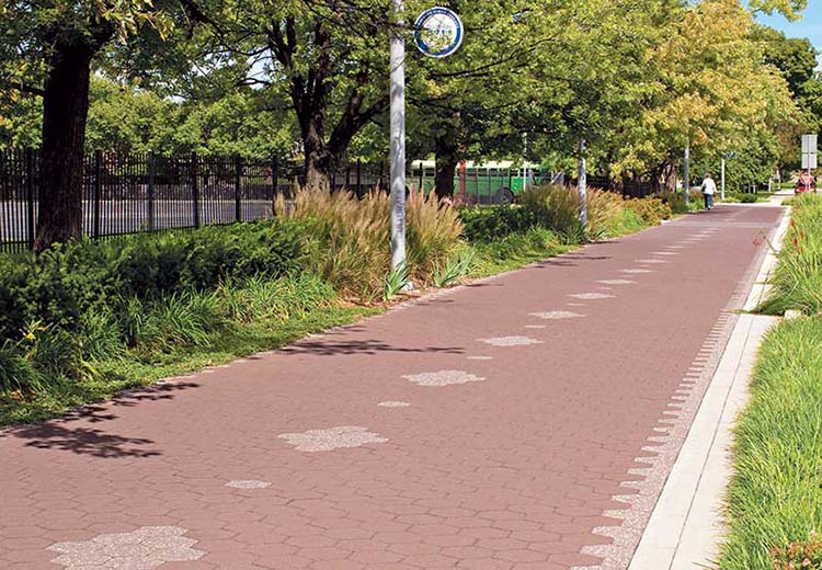 Tree-lined bike path paved with red hexagon Hanover asphalt tiles. Lighter tiles create a center diamond pattern and edging