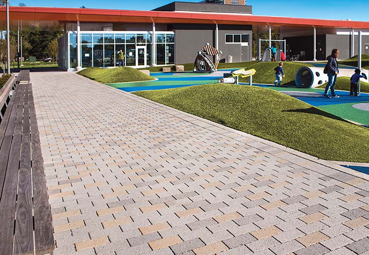A Hanover permeable brick pathway encircles an open play area.