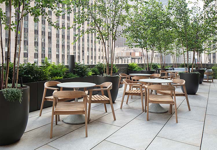 Large rectangular Hanover porcelain tiles on a high-rise balcony that are patterned to look like natural stone. Several sets of tables and chairs are mixed in with planters.