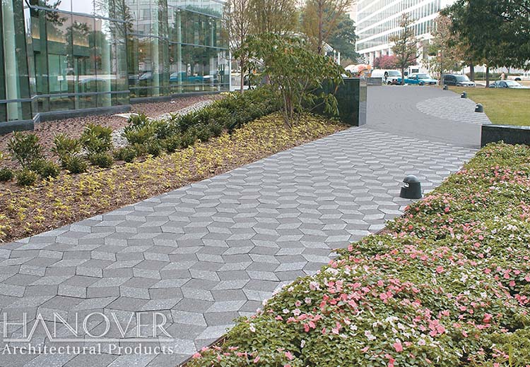 A walkway passing a large corporate building. The walkway has a pattern of Hanover 3D diamond-shaped pavers in alternating light and dark grey tones.