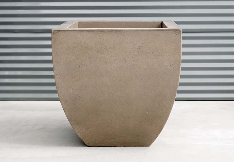 Form and Fiber Essentials rounded square concrete tall planter in front of corrugated metal wall