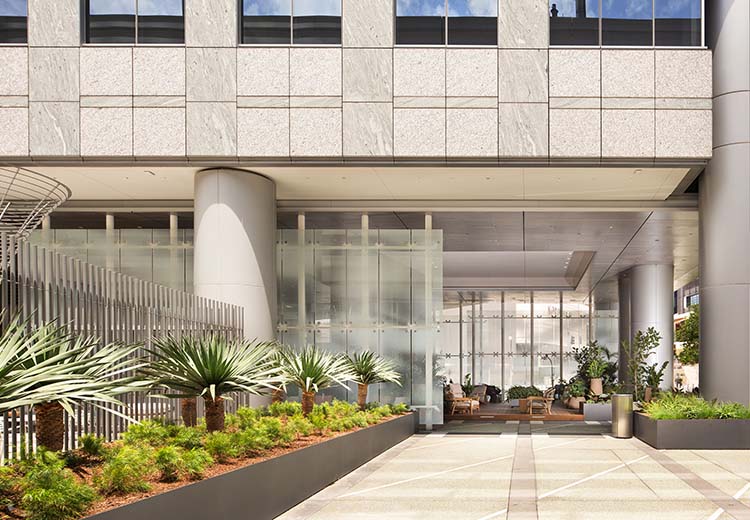 Outside of a high-rise office building with a porte-cochere and landscaping in Form and Fiber custom aluminum boxes
