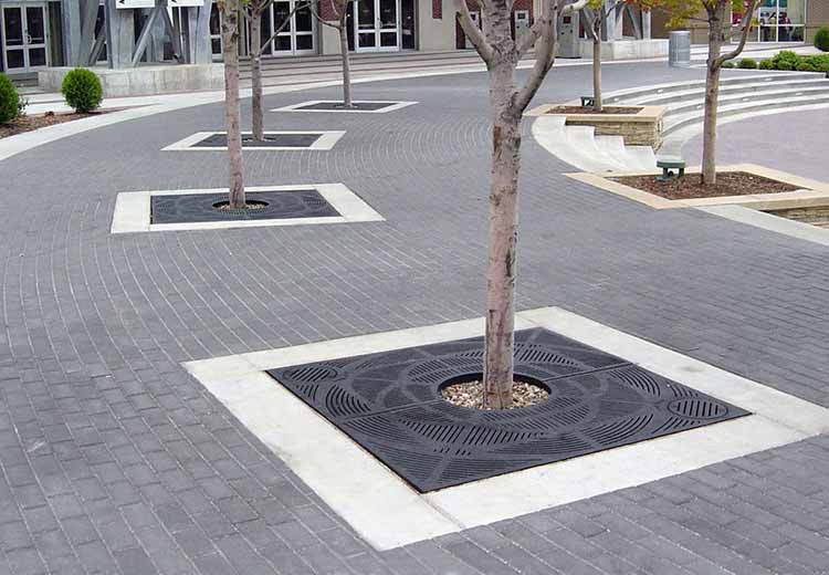Circular corporate courtyard with Ironsmith Camelia-style pavers and decorative grates at the base of the trees.