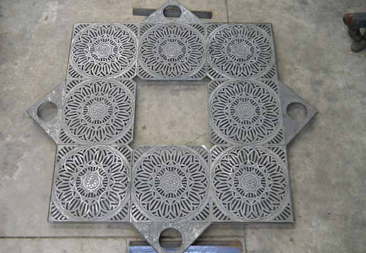 Ironsmith custom-case iron tree grate in a grey-tone metal with an intricate circular pattern